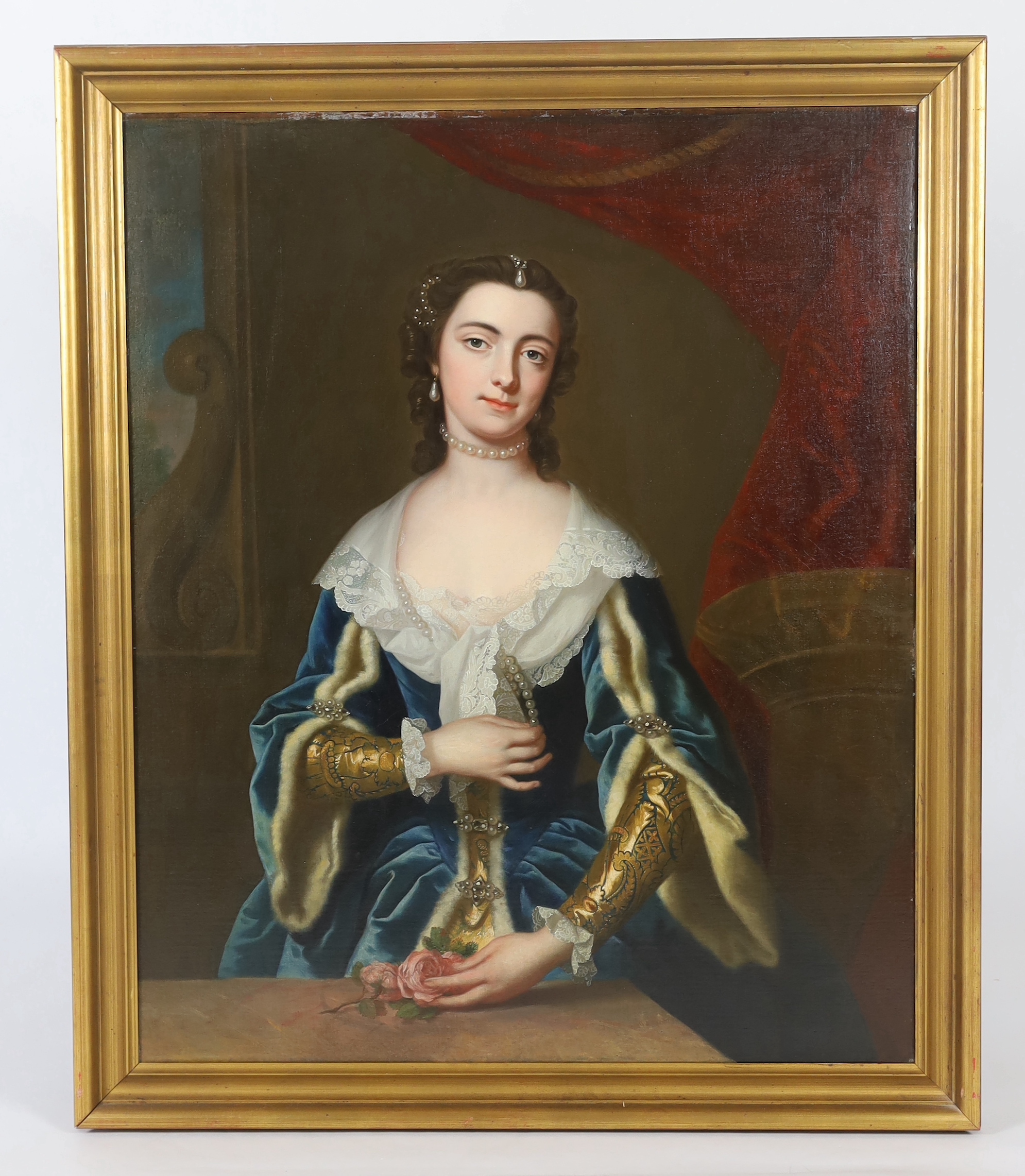 Thomas Bardwell (British, 1704-1767), Portrait of a lady standing half length wearing a lace trimmed blue velvet dress draped with pearls, her hand resting upon pink roses upon a ledge, oil on canvas, 101 x 83cm